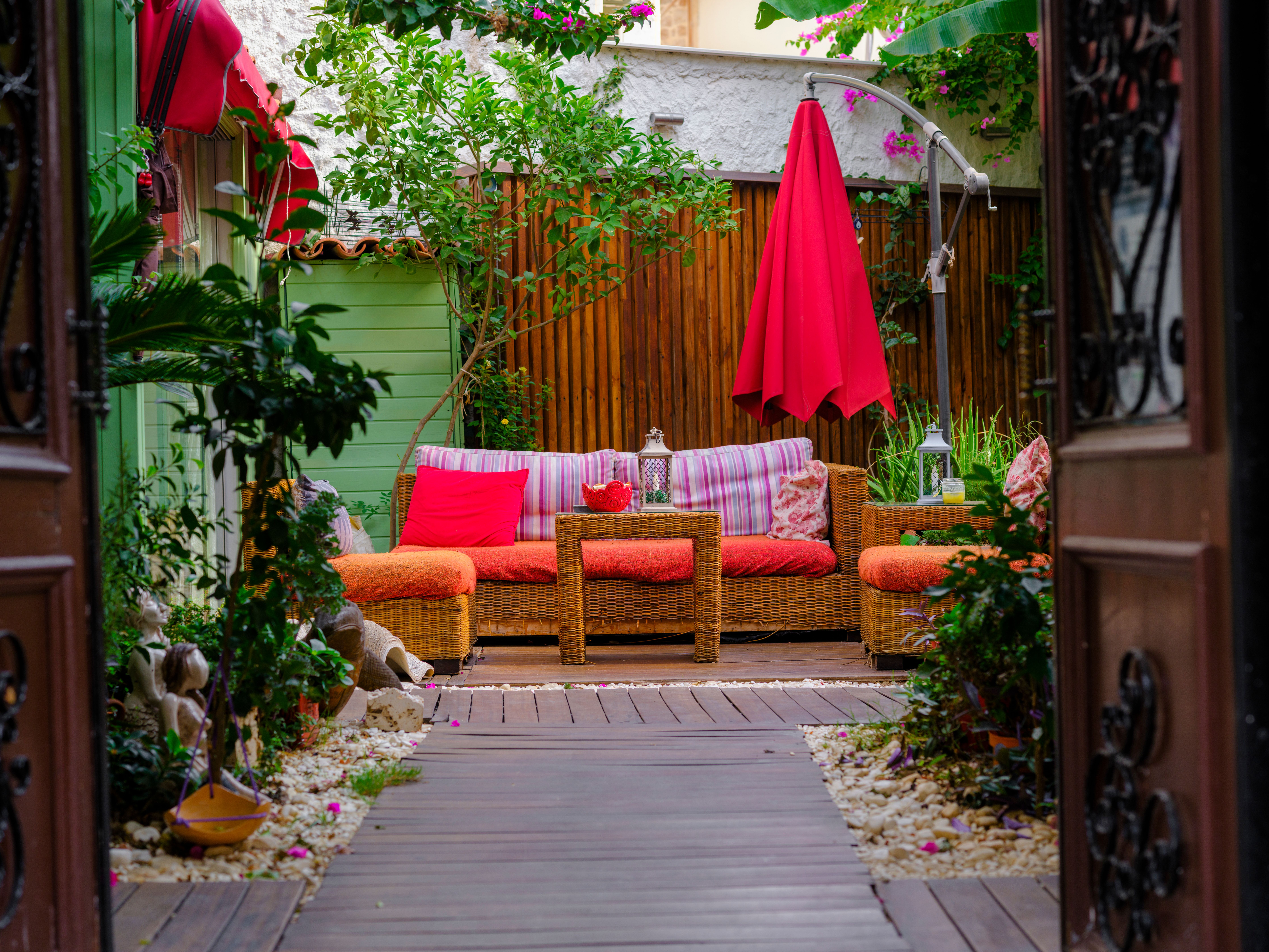 Wicker patio furniture with bright cushions and abundant greenery creating a welcoming garden retreat.