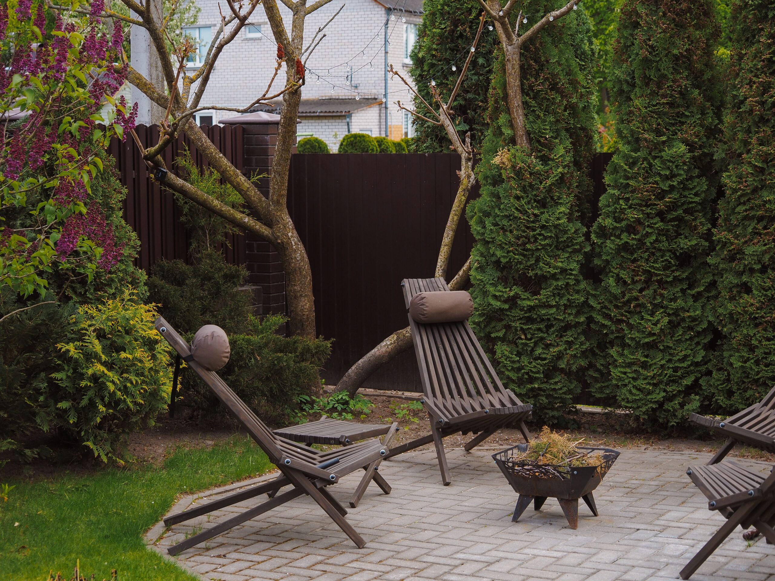 Cozy small backyard with wooden lounge chairs surrounded by lush greenery, illustrating a garden retreat makeover.